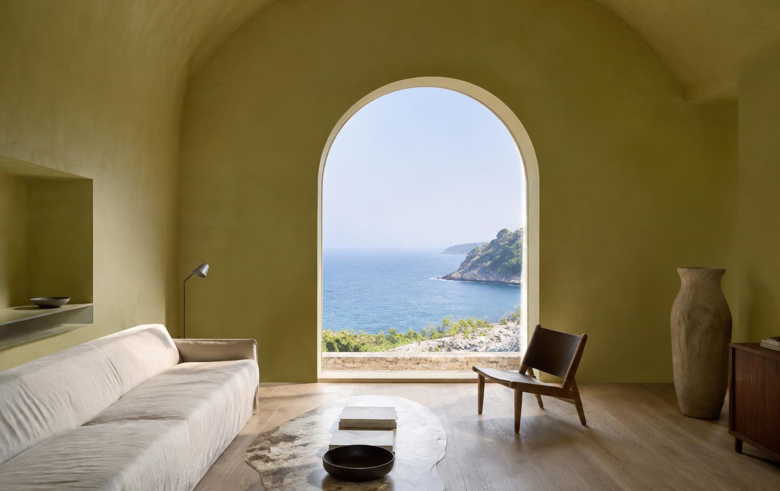Arched window framing the Mediterranean in a quiet lime-plaster room
